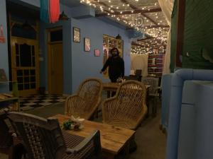 a man standing in a room with a table and chairs at The Kashi Baba Homestay in Dharamshala