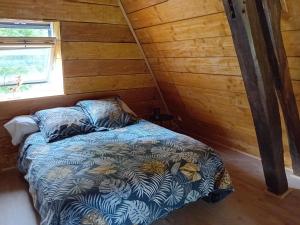 een slaapkamer met een bed in een houten hut bij Paisible Cahute in La Poterie-Mathieu