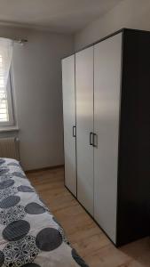 ポラントリュイにあるAppartement meubléの白いキャビネットとベッド付きのベッドルーム1室 +7枚の写真
