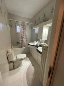 a white bathroom with a toilet and a sink at Katerina's house in Kalopigado
