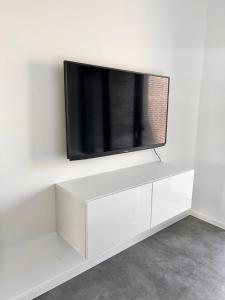 a flat screen tv sitting on top of a white entertainment center at Neubau Luxus 2 Zimmer Apartment in Mönchengladbach