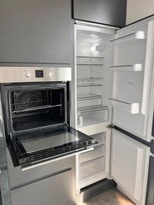 an empty refrigerator with an open oven in it at Neubau Luxus 2 Zimmer Apartment in Mönchengladbach