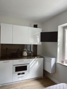 a white kitchen with white cabinets and a window at Nidos Baltija in Nida