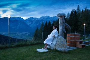una mujer sentada en una roca junto a un árbol en Alpenrelax Krepperhütte en Volders