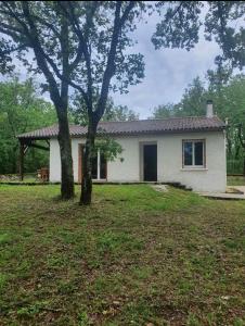 una casa bianca con un albero nel cortile di La maison dans les bois a Crayssac