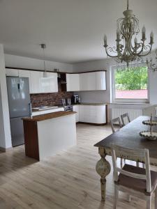 a kitchen with white cabinets and a table and a chandelier at Apartament nad jeziorem Zamkowym in Wałcz +17 photos