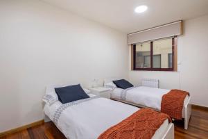 dwa łóżka w pokoju z oknem w obiekcie Apartamento Lua w mieście Milladoiro