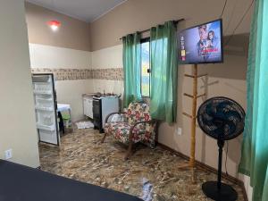 um quarto com uma televisão, uma cadeira e uma secretária em Loft praia do pontal, arraial do cabo Rj em Arraial do Cabo