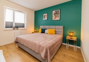 オルシュティンにあるApartament Kormoranのベッドと緑の壁のある寝室