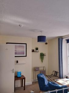 a living room with a blue chair and a table at Lyndale Guest House in Weymouth