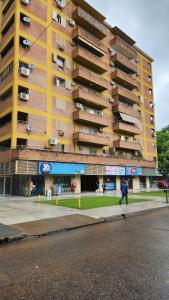 Un edificio alto y amarillo con una persona caminando frente a él. en Encantador hogar en Tucumán, en San Miguel de Tucumán