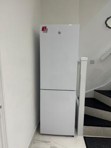 a white refrigerator in a room with a staircase at The Opulence - 5 Star in Burnley