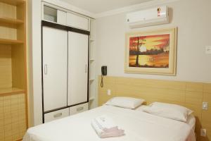 ein Schlafzimmer mit einem Bett und einem Gemälde an der Wand in der Unterkunft diRoma Rio Quente 1km do Hot Park in Rio Quente