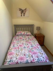 a bedroom with a bed with a floral bedspread at Sineag's Cottage in Pollachar