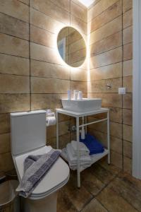 a bathroom with a sink and a toilet and a mirror at ASTERIA PEARL VILLA 2 with Rooftop Jacuzzi in Tigaki