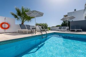 a pool with chairs and umbrellas next to a building at ASTERIA PEARL VILLA 2 with Rooftop Jacuzzi in Tigaki