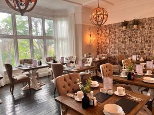 a restaurant with tables and chairs and windows at Roomours Hotel with Private Car Park in Llandudno