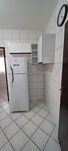 a kitchen with a refrigerator and a clock on the wall at Apto 201 Parque Via Verde - Mobiliado 2 quartos in Jaraguá do Sul
