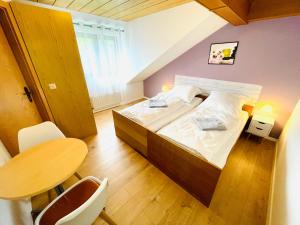 Un pequeño dormitorio con una cama y una mesa. en Pension Spatzennest, en Bad Rappenau
