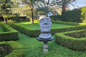 a statue of a face in the middle of a garden at Das GANZE Chateau Thor - bis zu 22 Personen in Lontzen