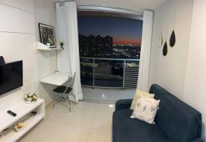 a living room with a blue couch and a large window at Pôr do Sol DF Plaza in Brasília