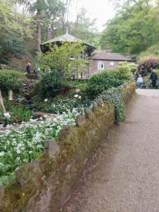 a stone wall with flowers in front of a house at Jasmine cottage-1 King bed room, 40 mins to Cotswolds 90 mins to Oxford and Bath in Great Malvern