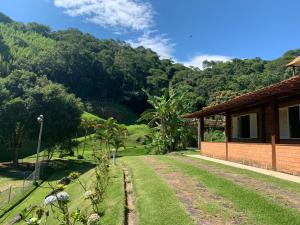 a house with a garden and mountains in the background at Refúgio da Mata - Chalé Araucária in Paty do Alferes
