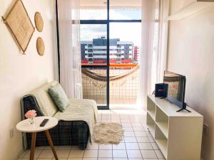 ein Wohnzimmer mit einem Sofa, einem TV und einem Fenster in der Unterkunft RF-86: Apê completo e aconchegante na Ponta Verde in Maceió