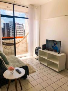 ein Wohnzimmer mit Fernseher und Sofa in der Unterkunft RF-86: Apê completo e aconchegante na Ponta Verde in Maceió