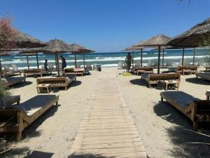 a beach with many chairs and umbrellas and the ocean at Top strandhuis aan zee! in Néa Meságkala