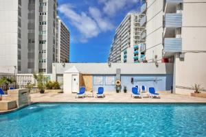 a swimming pool with blue chairs and buildings at Apartamentos en excelente Zona Condado, San Juan, Puerto Rico in San Juan