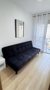 a black couch in a living room with a window at Aly Home in Castellón de la Plana +5 photos
