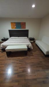 a bedroom with a bed and a couch and wooden floors at Hotel Paraiso in Mexico City