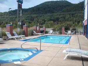 a swimming pool with chairs and a table and a mountain at Mountain Inn & Suites in Erwin
