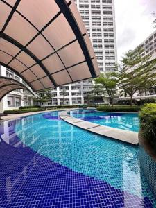 a large swimming pool with blue water in a city at Cozy Condo in Taguig in Manila