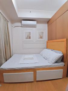 a small bedroom with a bed with two drawers at Cozy Condo in Taguig in Manila