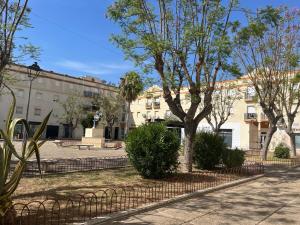 a fence with trees in front of a building at Casa Gran Cinema in Sanlúcar de Barrameda