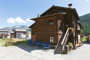 una casa in legno con sedie blu di fronte di Bait Vegl a Livigno