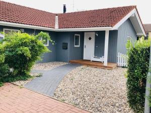 a blue house with a wooden porch and a driveway at Holiday home Dan Huus Marie in Großenbrode