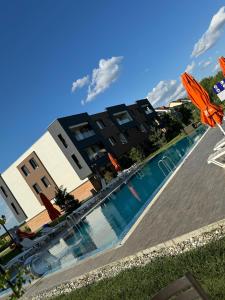 a swimming pool in front of a building with a resort at Libertatii Gardens Poolside AIRPORT&THERME in Otopeni