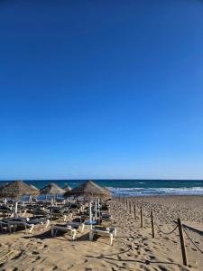 a group of beach chairs and umbrellas on a beach at Julia's apartment in Marbella