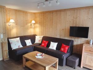 sala de estar con sofá negro y almohadas rojas en Apartment Sérac en Méribel
