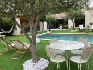 a table and chairs around a tree next to a pool at La Maison 1440 in L'Isle-sur-la-Sorgue
