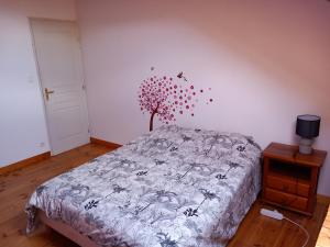 a bedroom with a bed with a tree on the wall at Le Gîte de Nadine in Belvezet +2 photos
