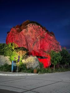 a large red rock sitting on the side of a road at Holiday Guest-House in Përmet