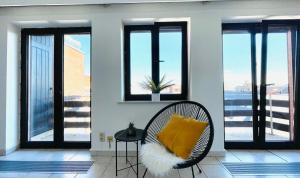 a wicker chair with a yellow pillow on a balcony at Studio Square - zonrijke studio - zuidgericht balkon - dichtbij strand in Middelkerke