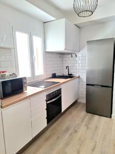 una cucina con armadi bianchi e frigorifero in acciaio inossidabile di La molina, apartamento Cebada a Corralejo