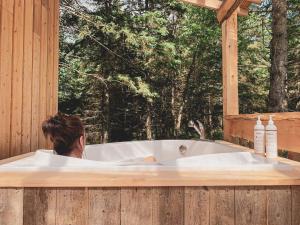 a person sitting in a bath tub looking out a window at Chalet Le Madison Refuge nordique et ciel étoilé au pied du Mont-Mégantic in La Patrie