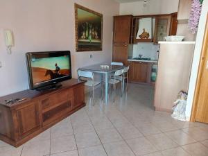 a living room with a tv and a table and a kitchen at Ma-gi house in Castelnuovo Cilento