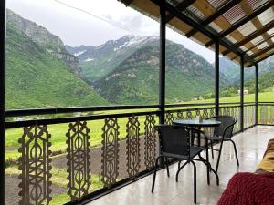 a balcony with a table and chairs and mountains at Guest House Nino in Mestia